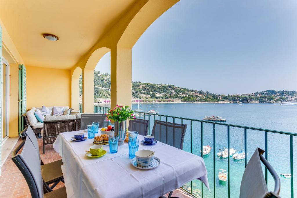 une table sur un balcon avec vue sur l'eau dans l'établissement EDEN VIEW AP4469 by Riviera Holiday Homes, à Villefranche-sur-Mer