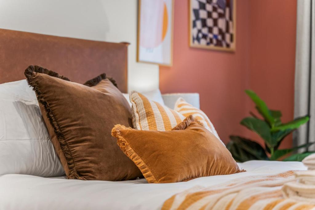 a bed with brown and white pillows on it at Luxury 2-Bed with Balcony & Secure Parking in Leeds