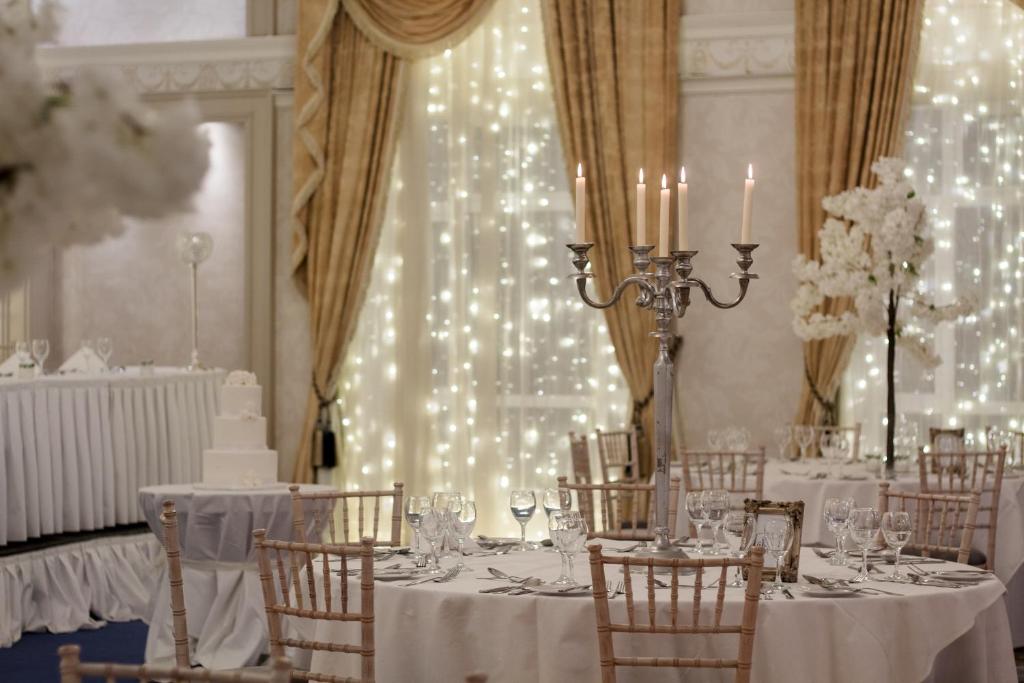 a dining room with white tables and chairs and lights at The Newgrange Hotel in Navan