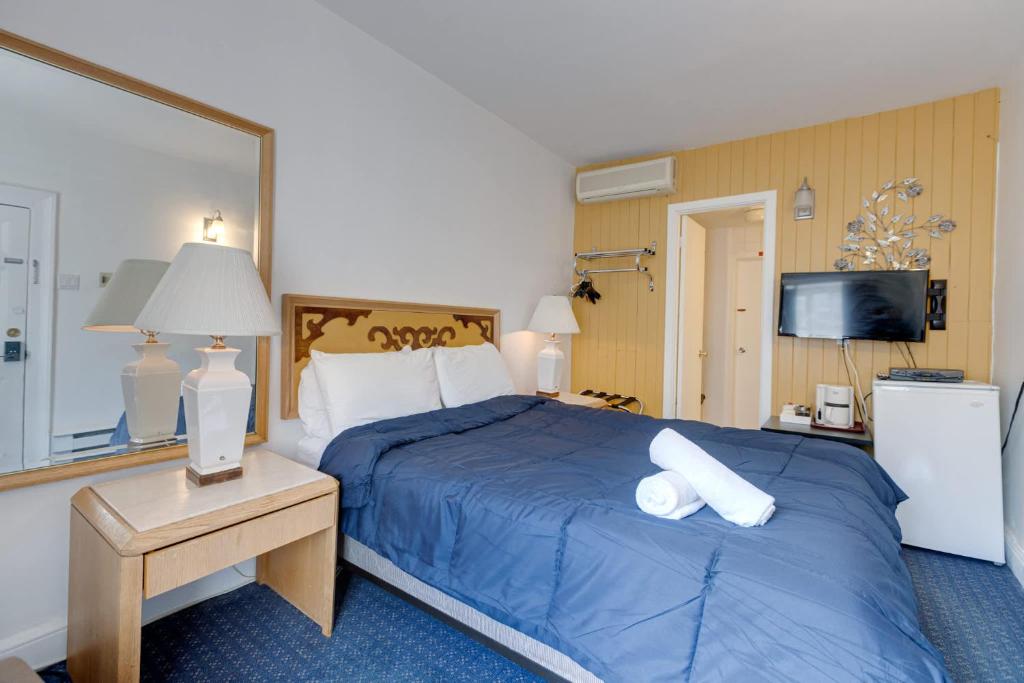 a hotel room with a bed with a blue comforter at Comfort Room - Hotel Le Cavalier by M11 in Quebec City