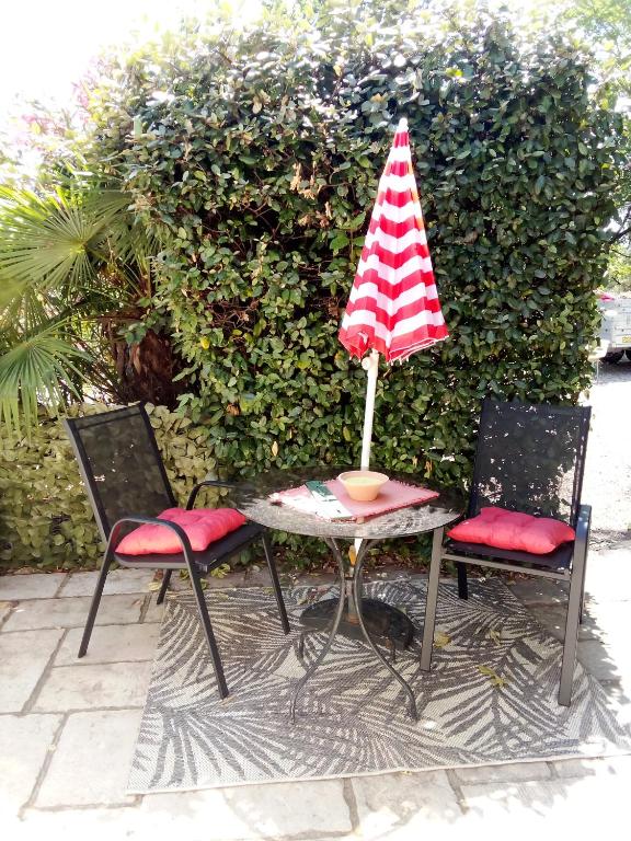 une table avec un parasol rouge et blanc et deux chaises dans l'établissement Petit Studio, à Lorgues