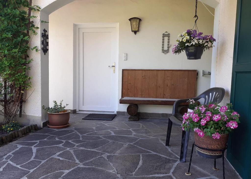 a porch with a bench and flowers on the floor at Ferienwohnung Feßler in Steingaden