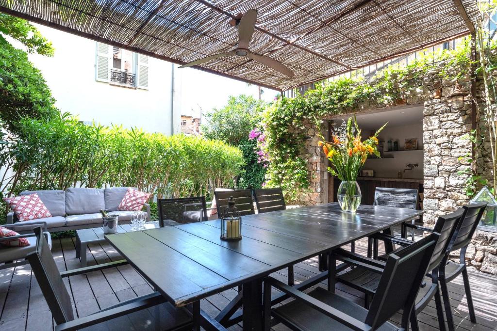 戛纳Villa Le Loft by Festif Azur 4-Star 200m2 House with Garden, 5-Min Walk to Palais des Festivals and Beaches的户外庭院配有木桌和椅子