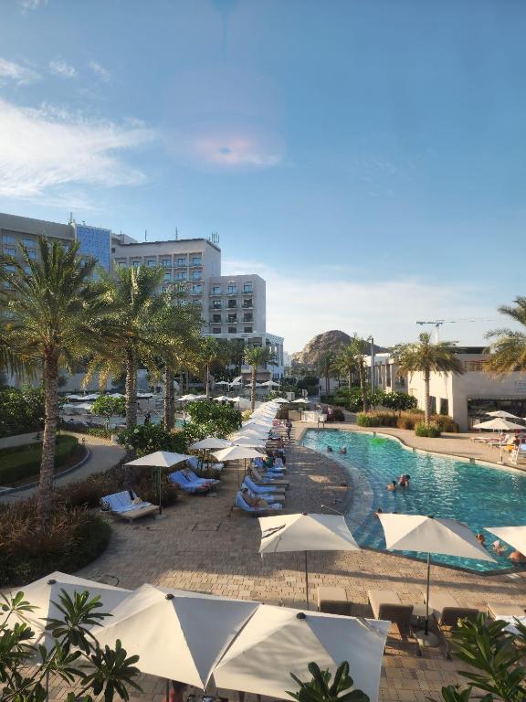 Ocean View Address Fujairah Beach Resort的一个带遮阳伞的游泳池和一个度假村