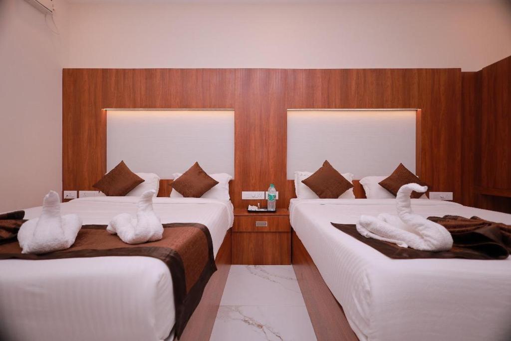 two swans sitting on two beds in a hotel room at Hotel Sahaya Arasi in Kovakulam