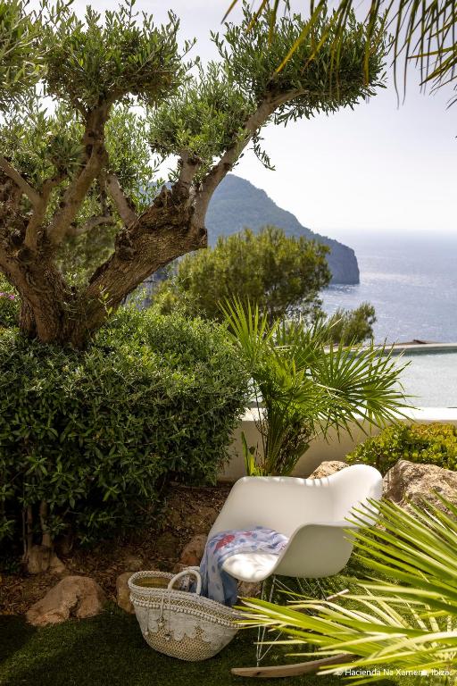 a white chair sitting on the grass next to a tree at Hacienda Na Xamena, Ibiza in Na Xamena