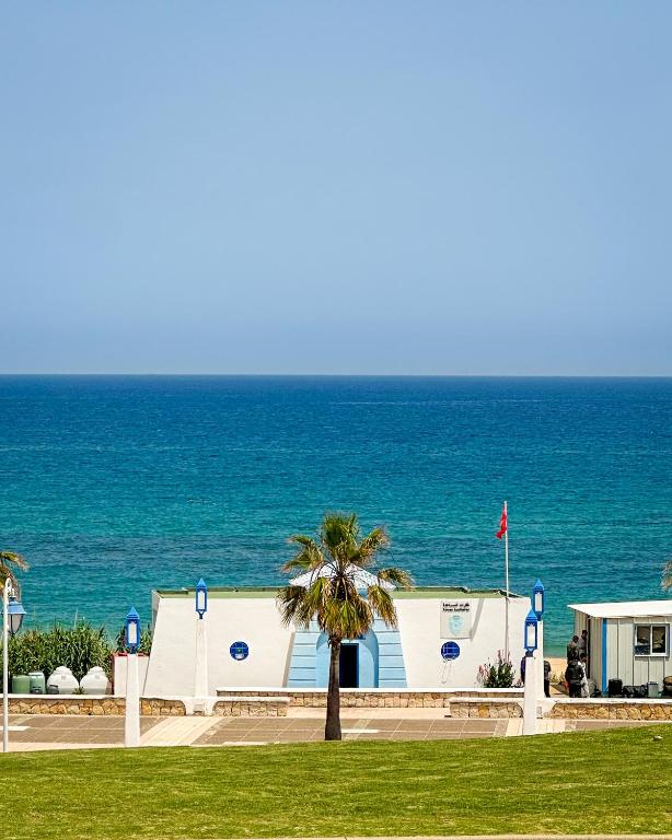a building with a palm tree in front of the ocean at Alcudia Smir Complex piedras del Mar in Fnidek
