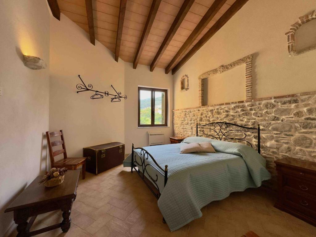 a bedroom with a bed and a stone wall at Gli appartamenti sul Portico - La Forchetta e Il Cucchiaio in Orco Feglino