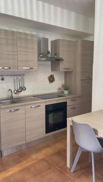 a kitchen with wooden cabinets and a table with a chair at Casa vacanza Foceverde lido in Lido di Latina