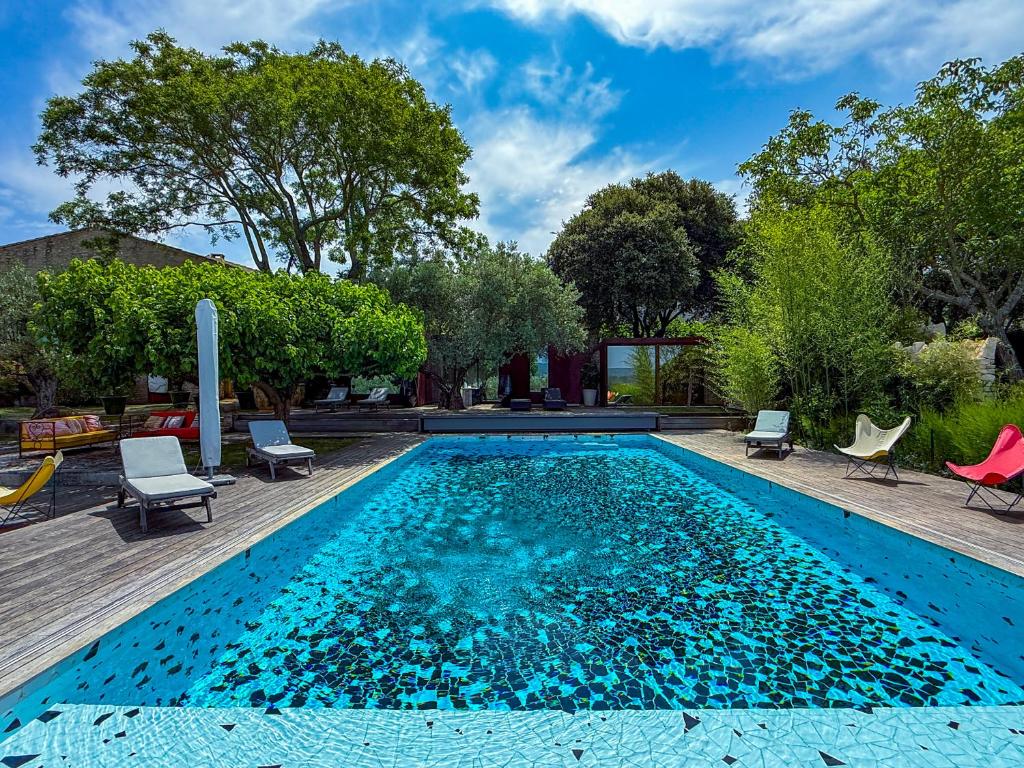 une piscine avec de l'eau bleue dans une cour dans l'établissement Le Poolhouse, Lodge avec piscine au coeur du Luberon, à Saint-Saturnin-lès-Apt