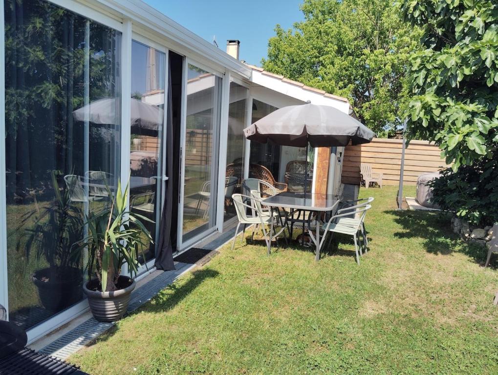 une table et des chaises avec un parasol sur une maison dans l'établissement L'Edenwine jardin clos et spa privatif, à Doulezon