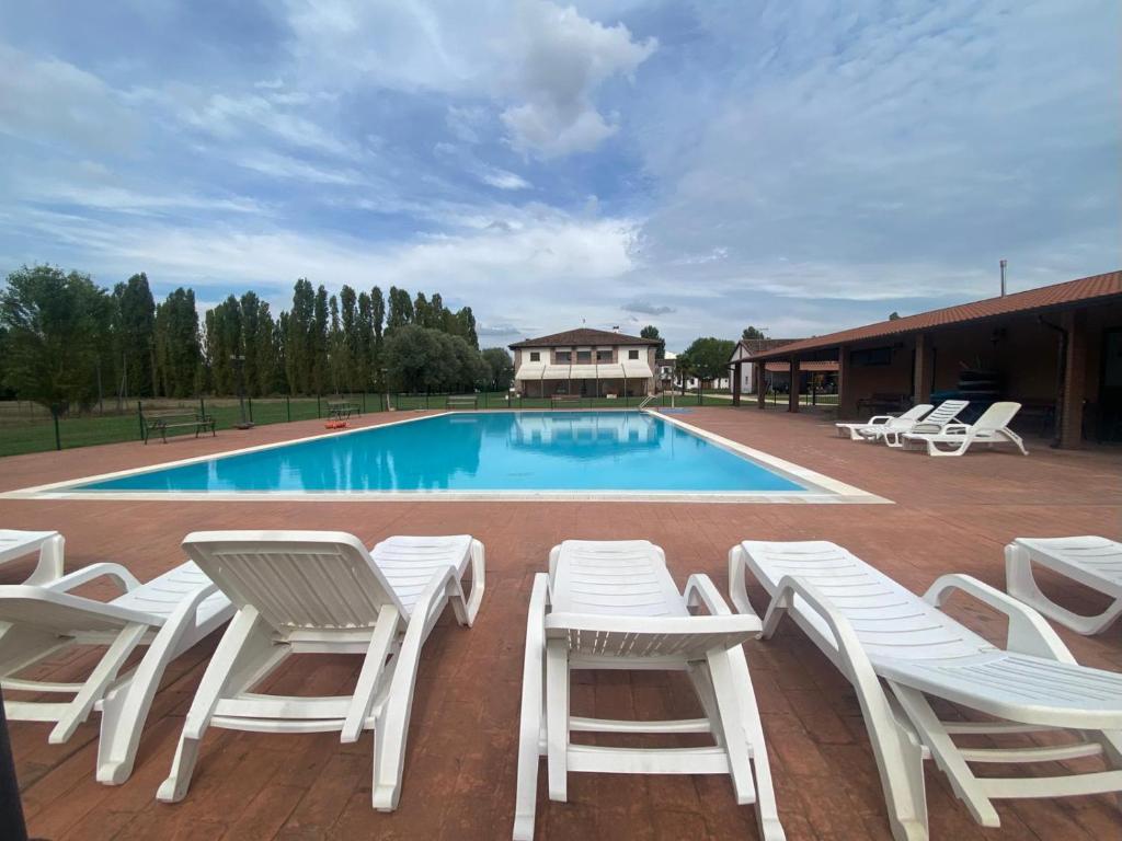 a group of white chairs and a swimming pool at Agriturismo La Bisa in Trecenta