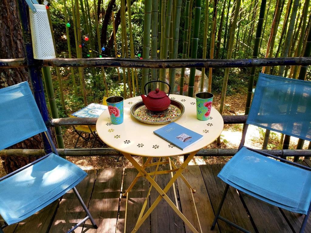 une petite table avec une théière et deux chaises dans l'établissement La Yourte aux Bambous en Cévennes, à Saint-André-de-Majencoules