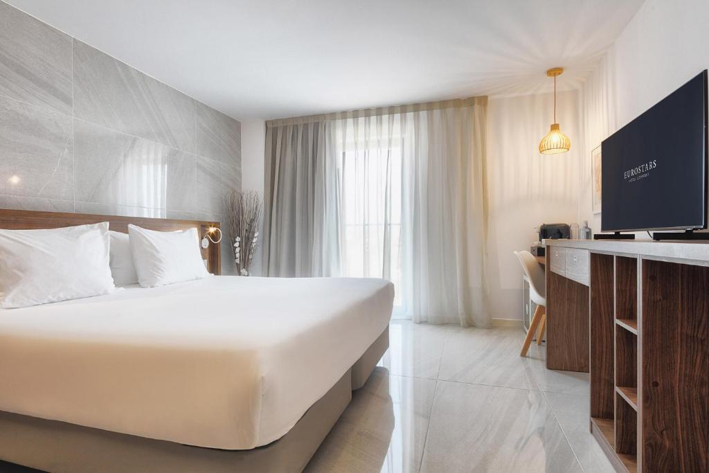 a hotel room with a large bed and a television at Eurostars Puerto de Ibiza in Ibiza Town