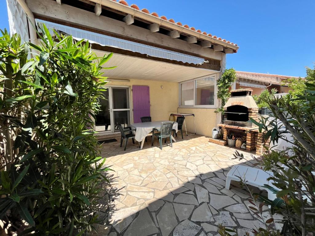 d'une terrasse avec une table et un four à pizza. dans l'établissement Belle villa 5 couchages 2 chambres 2 terrasses piscine commune dans résidence securisée à 200m de la mer LRMA23, à Portiragnes