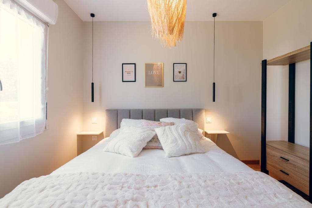 une chambre avec un lit avec des draps blancs et un lustre dans l'établissement L'élegant, climatisé et rénové - Appart'hôtel Chez MV, à La Ferté-Gaucher