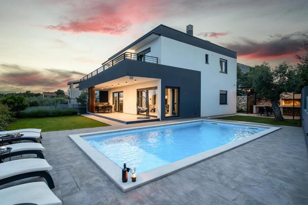 a house with a large swimming pool in the backyard at Villa Kali by IstriaLux in Krnica