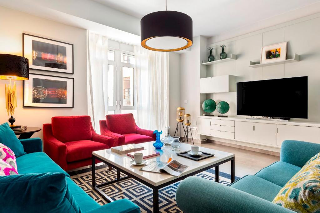 a living room with red chairs and a tv at Genteel Home Albareda in Seville