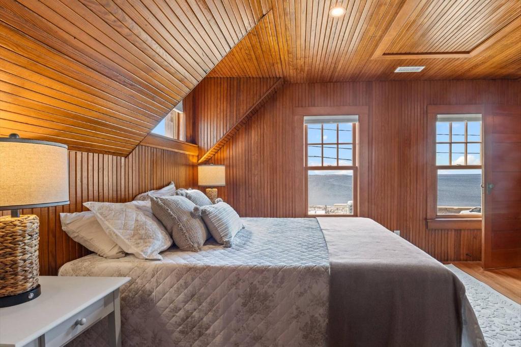 a bedroom with a bed with wooden walls and windows at Life of Reilly - Scituate in Scituate