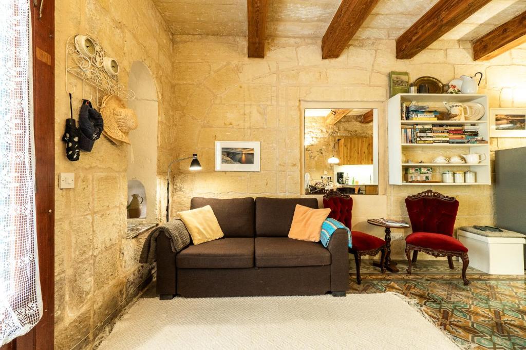 a living room with a couch in a stone wall at Cosy Haven, 96 Triq il-Karita', Victoria Gozo in Victoria