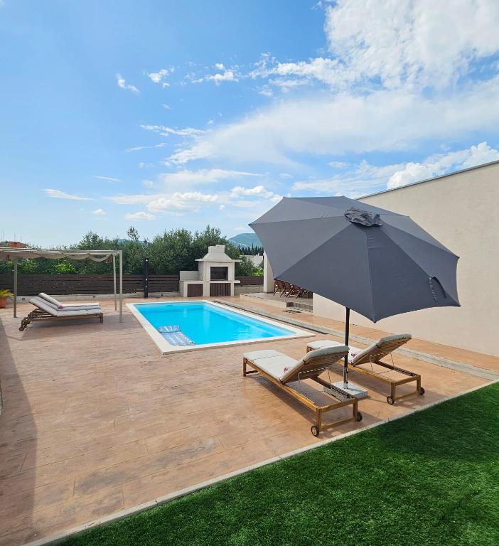 eine Terrasse mit Sonnenschirm und ein Swimmingpool in der Unterkunft SunN Joy in Kaštela