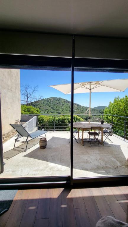 - une vue sur la terrasse dotée d'une table et d'un parasol dans l'établissement Maison au cœur d'un village, vue sur les montagnes, à Bélesta
