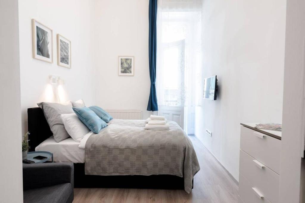 a white bedroom with a bed and a window at Modern studio with AirCon and balcony in the center in Budapest
