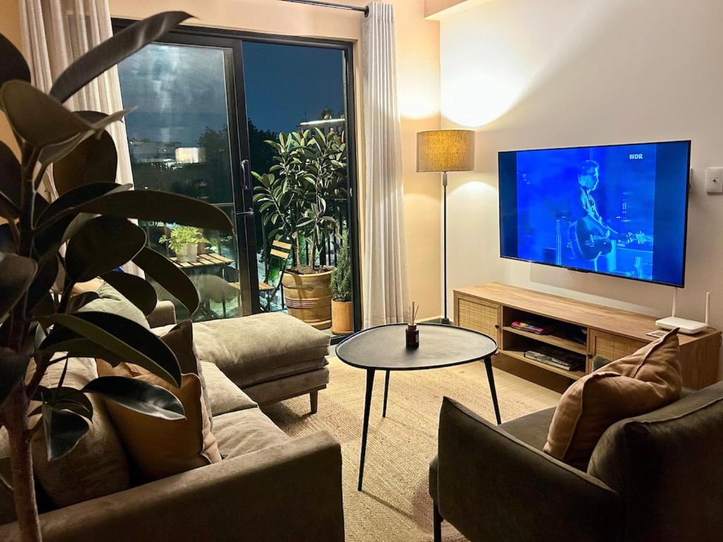 un soggiorno con una TV, un divano e un tavolo di HUNAB Roma Apt - Pool, Coworking and Gym NEW a Città del Messico