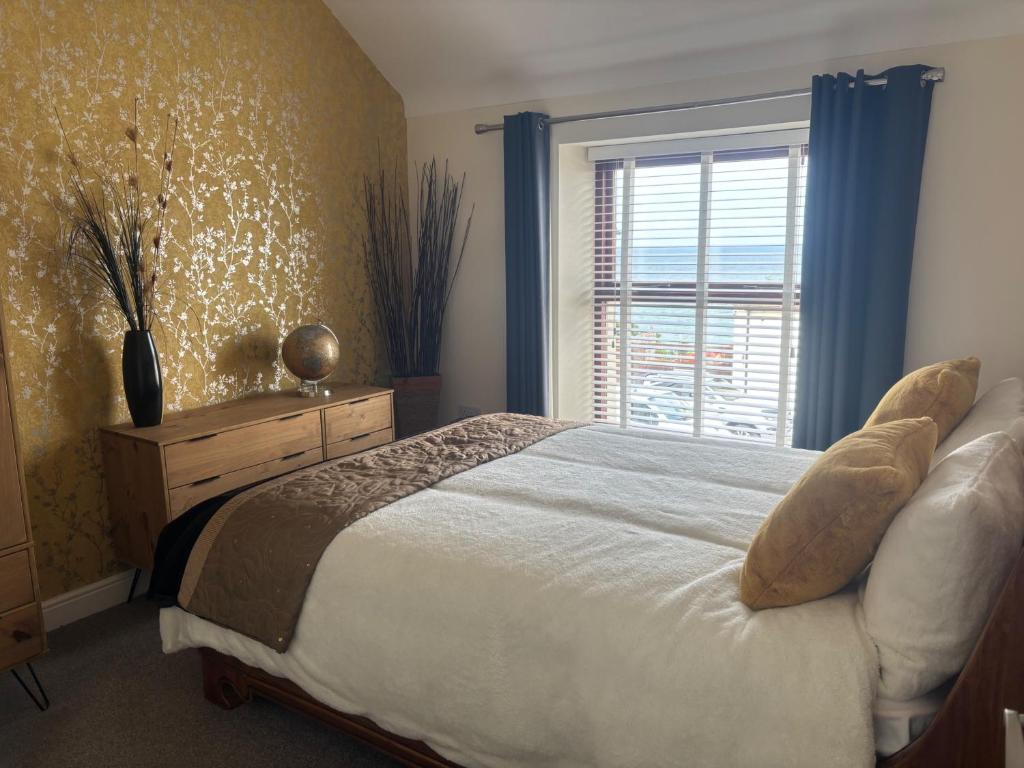 Un dormitorio con una cama y una ventana con cortinas azules. en Penmaenmawr Coastal Retreat, en Penmaen-mawr
