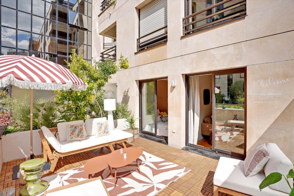un patio avec une table, des chaises et un parasol dans l'établissement Appartement spacieux avec terrasse proche hôpital américain, à Levallois-Perret