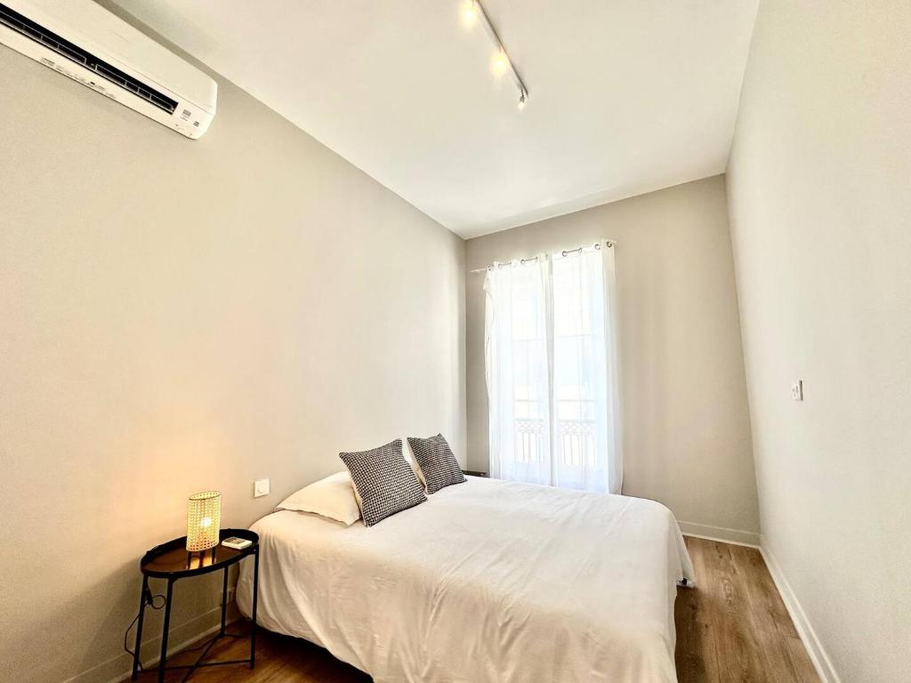 una camera bianca con un letto e una finestra di Appartement au coeur de Nice pour 4 - Clim & Wifi a Nizza