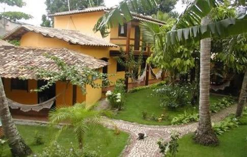 una casa amarilla con un patio con palmeras en Pousada O Cantinho, en Arraial d'Ajuda