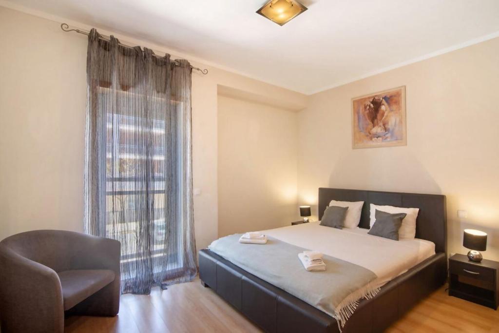 a bedroom with a bed and a chair and a window at HolidaysPT - MyOasis I - T2 Apartment in Olhão
