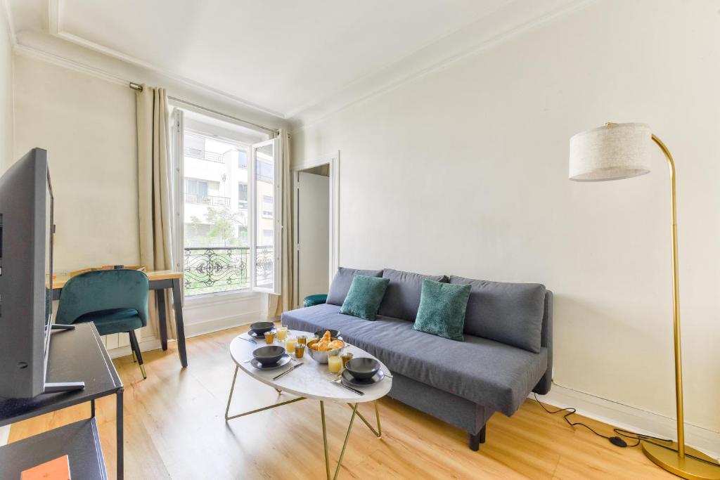 un salon avec un canapé et une table dans l'établissement Quiet & Refurbished 1BR Parisian Retreat-Paris 16, à Paris