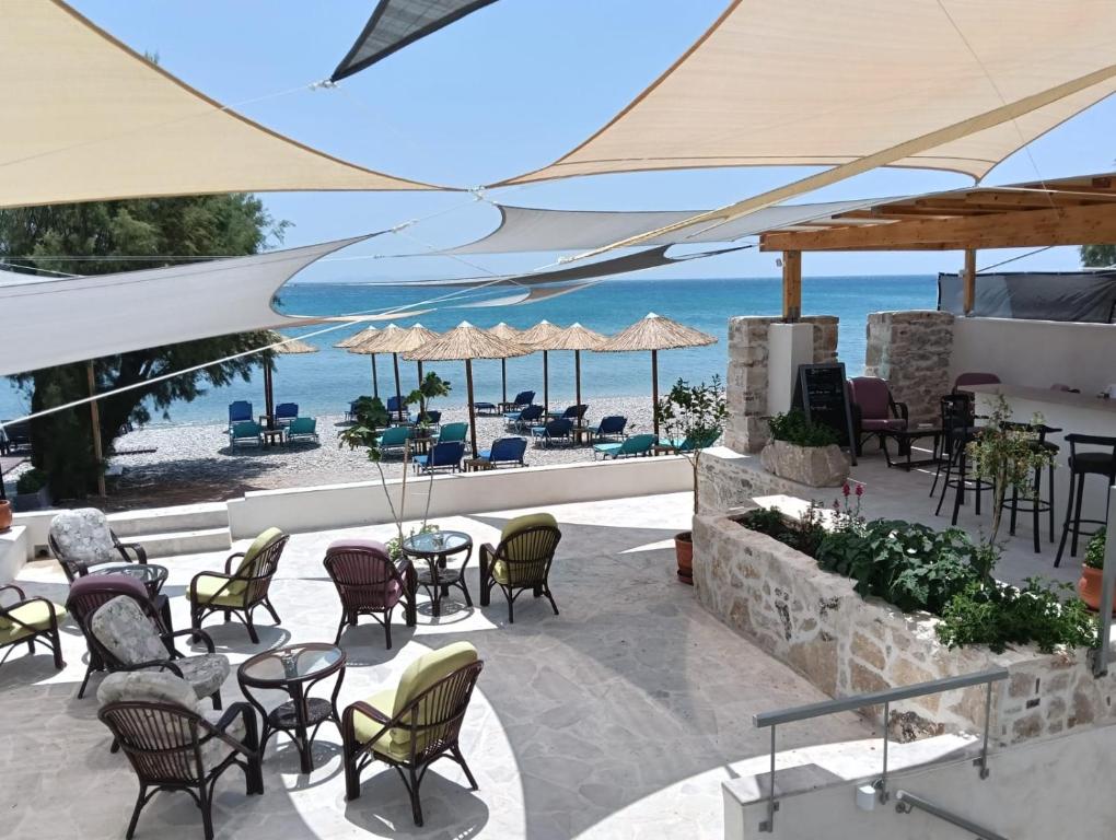 a patio with chairs and tables with the beach in the background at Phil Samosflats Beachfront Maisonettes in Potokáki
