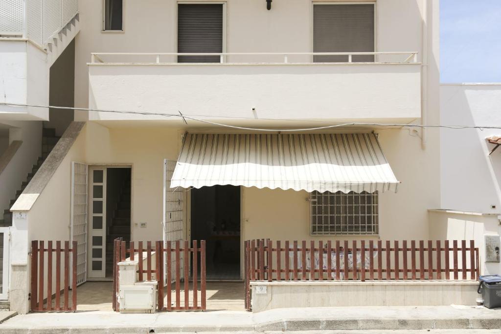 a white building with awnings and a balcony at Casa Vacanza Teresa con balcone in Torre Mozza