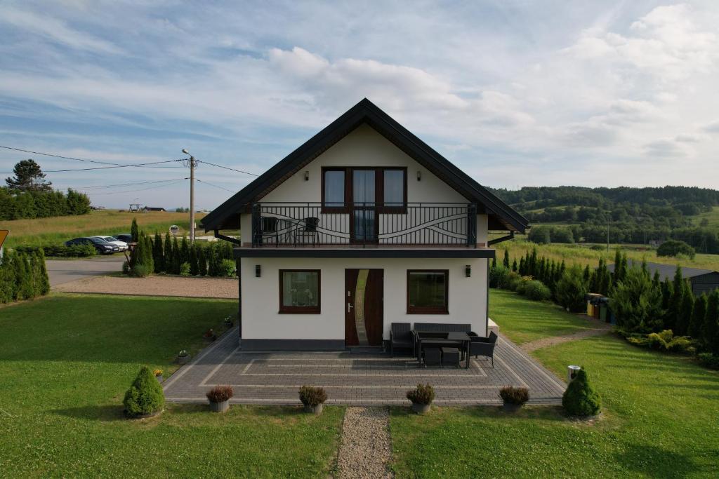 ein kleines weißes Haus mit schwarzem Dach in der Unterkunft Domek letniskowy Elizjum in Myczków