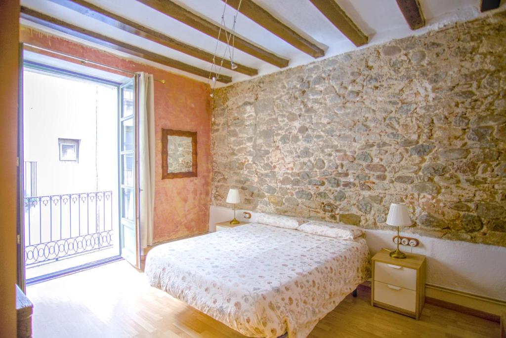 a bedroom with a bed and a stone wall at La Lleona Apartment in Girona