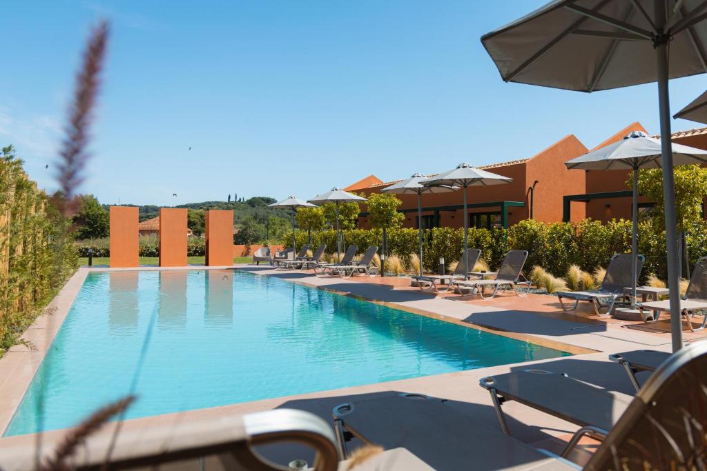 ein großes Schwimmbecken mit Liegestühlen und Sonnenschirmen in der Unterkunft Cape Resort in Peroulades