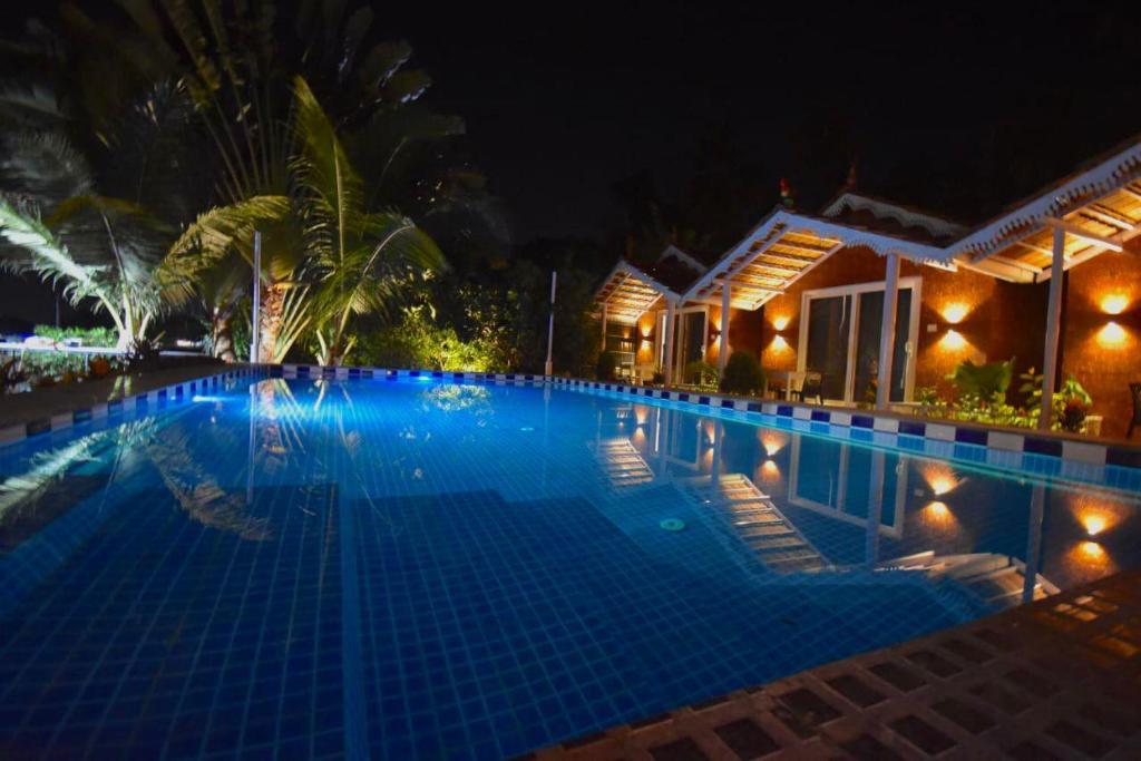 a large swimming pool at night at Golden Rice Resort & Cottages in Candolim