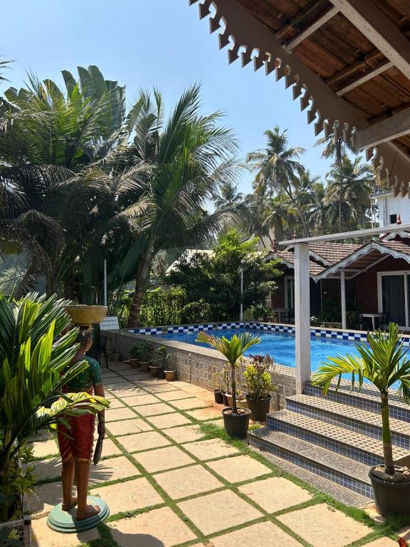 a man standing on a lawn near a swimming pool at Golden Rice Resort & Cottages in Candolim