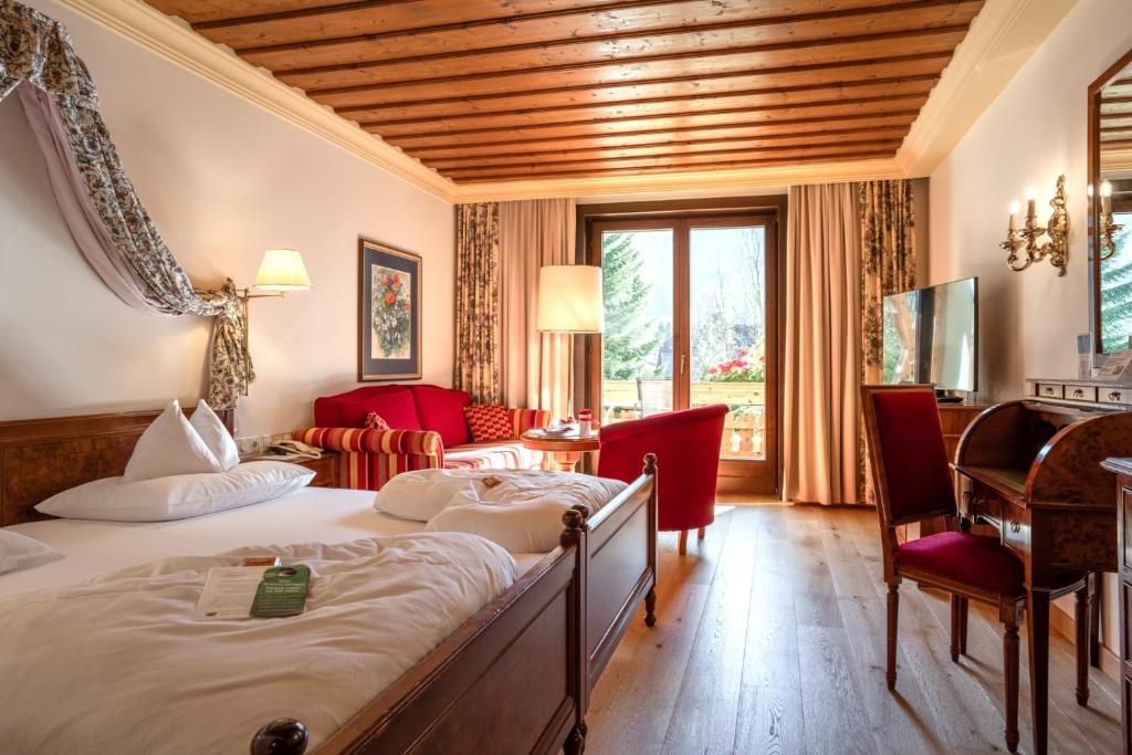 a hotel room with a large bed and a desk at Thermenwelt Hotel Pulverer in Bad Kleinkirchheim