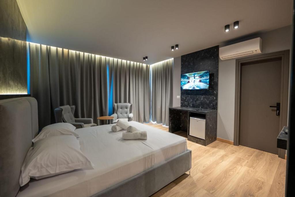 ein Schlafzimmer mit einem großen weißen Bett und einem Fernseher in der Unterkunft Ersa Luxury Rooms in Sarandë