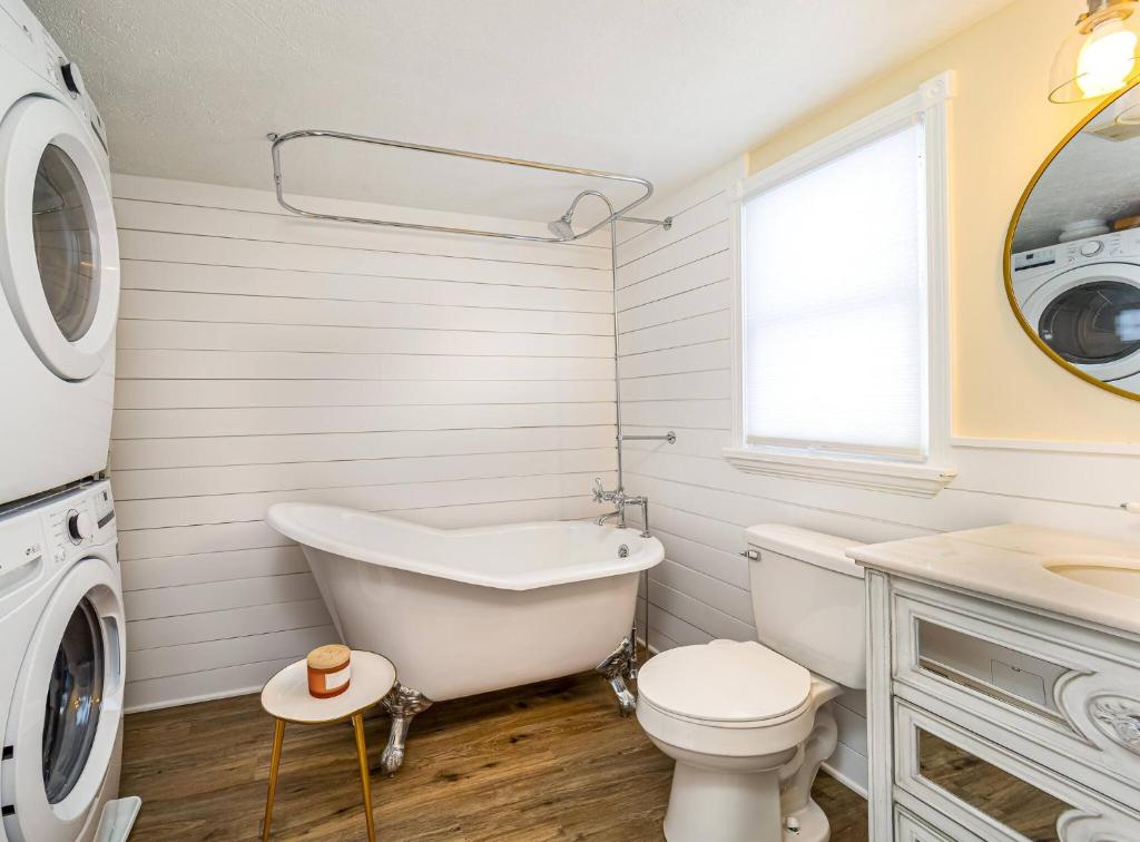 a bathroom with a tub and a toilet and a washing machine at Stylish 2BR n Old Town Greenwood in Greenwood
