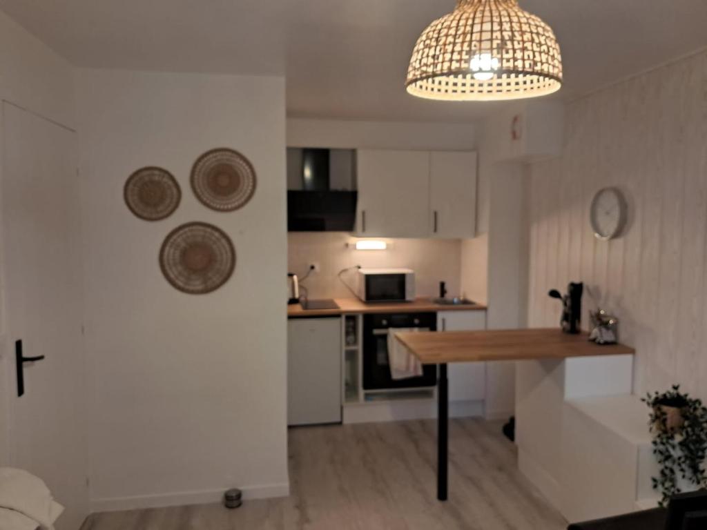 une cuisine avec une table et un lustre dans l'établissement Le temps d'une pause, à Villers-sur-Mer