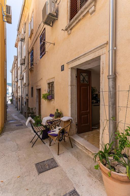 an alley with tables and chairs in front of a building at Ilir Apartman in Cres