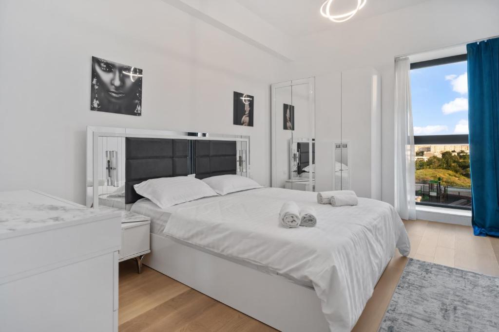 a white bedroom with a large bed and a window at Verdi Park Designer Condo in Bucharest