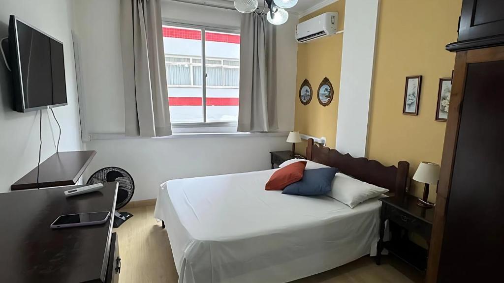 a bedroom with a bed and a desk and a television at Apto Almeida e Moraes charmoso passos da praia de BC in Balneário Camboriú