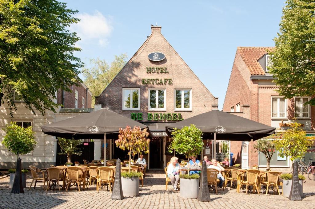 un restaurant avec des tables et des parasols en face d'un bâtiment dans l'établissement Hotel Restaurant De Bengel, à Eersel