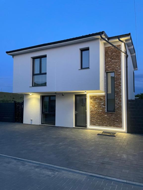 a white house with a driveway in front of it at Emerald Home in Suceava